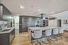 Contemporary kitchen featuring dark wood-finish cabinetry, a large central island with a stone-finish countertop, integrated stainless steel appliance