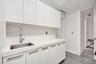 Custom white cabinetry, solid surface countertop, stainless steel undermount sink, high-arc chrome faucet, and tile flooring