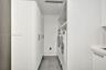 Laundry space featuring floor-to-ceiling white cabinetry, expansive open shelving, stone-finish tile flooring, and integrated white appliances