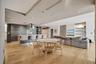 Open concept interior featuring wide-plank wood-finish flooring, custom dark-toned cabinetry, a stainless steel range hood, recessed ceiling lighting,