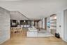 Open-concept interior featuring light wood-finish flooring, a kitchen with a stone-top island, custom cabinetry, and built-in shelving with integrated