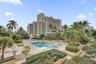 Resort-style pool area featuring a multi-level stone deck, integrated spa, and manicured tropical landscaping