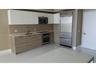 Kitchen featuring two-tone cabinetry with wood-grain finish lower cabinets and matte white upper cabinets, stainless steel appliances, integrated refr