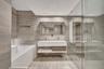 Floating dual vanity with integrated countertop, wall-to-wall linear tile surfacing, recessed ceiling lighting, glass-enclosed shower, and deep-profil