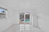 Interior space featuring white tile flooring, crown molding, double French doors, and built-in white cabinetry, with a perspective toward a screened p