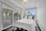 Sliding glass doors opening to a covered balcony, wood-finish flooring, recessed ceiling lighting, and custom window treatments
