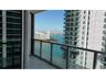 Covered balcony featuring glass pane railings, tile flooring, and water scenery
