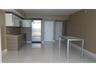 Kitchen featuring high-gloss white upper cabinetry, wood-finish lower cabinetry, stone countertops, stainless steel appliances, and large-format tile 