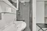 Bathroom featuring a wall-mounted vanity, stainless steel single-handle faucet, glass-enclosed shower with full-height tile, and integrated mirrored m