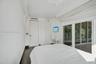 Room featuring dark wood-finish flooring, floor-to-ceiling sliding glass doors, built-in closet cabinetry, and minimalist white window treatments