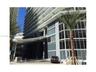 High-rise building exterior featuring a glass-paneled facade, cantilevered entryway canopy, and multiple private balconies