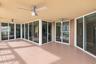 Covered outdoor terrace featuring wood-finish decking, multiple glass sliding doors, and dual ceiling fans