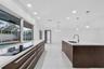 Kitchen featuring dark wood-finish cabinetry, solid-surface countertops, a center island with an undermount sink, porcelain tile flooring, and recesse