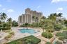 High-rise residential complex featuring a swimming pool, an attached hot tub, paved sun deck, and tropical landscaping