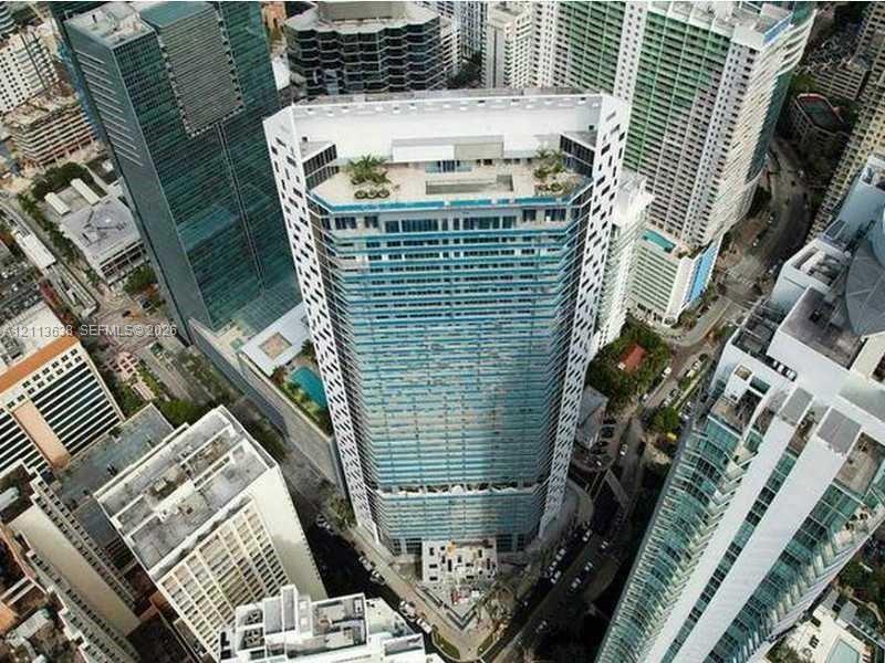 High-rise architectural structure with floor-to-ceiling glass windows, a rooftop terrace, an elevated swimming pool, and geometric facade detailing