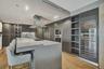 Kitchen featuring wood-finish flooring, a large island with a stone-surfaced countertop, integrated stainless steel appliances, dark wood-tone cabinet
