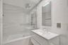 Bathroom featuring full-height wall tiling, a floating white vanity with an integrated basin, a frameless glass shower enclosure, a ceiling-mounted ra