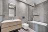 Bathroom featuring large-format grey tile wall cladding, wood-finish floating vanity with an integrated basin, wall-mounted toilet, and a glass-enclos