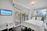 Dark wood-finish flooring, floor-to-ceiling glass sliding doors, private balcony with decorative railing, and ceiling-mounted light fixture with integ
