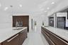 Kitchen featuring dark wood-finish cabinetry, solid-surface countertops, integrated wall oven, stainless steel dual-basin sink with pull-down faucet, 
