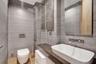 Wall-to-wall stone-finish paneling, wall-mounted toilet with chrome actuator, custom vanity with wood-finish countertop, rectangular vessel sink, and 