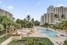 Resort-style community grounds featuring a swimming pool, integrated spa, tiled sundeck, and palm-lined landscaping