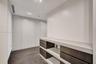 Built-in floor-to-ceiling cabinetry with white paneling, wood-finish flooring, custom low-profile shelving with dark-toned drawers, and recessed ceili