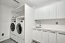 Laundry area featuring white flat-panel cabinetry, a quartz countertop, a stainless steel undermount sink with a gooseneck faucet, and integrated buil
