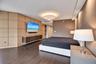 Custom millwork wood-panel wall, integrated floating cabinetry, wood-finish flooring, recessed ceiling lighting, and a drum-style pendant light fixtur