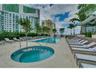 Swimming pool and circular spa with stone decking, metal handrails, and perimeter landscaping