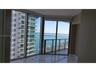 Floor-to-ceiling wrap-around windows, sliding glass door, private balcony with metal railing, and polished stone-finish flooring