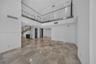 Double-height ceiling, polished stone flooring, glass panel mezzanine railing, recessed lighting, and staircase with metal handrail