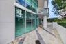 Outdoor terrace featuring floor-to-ceiling glass paneling, geometric stone paver inlay, concrete structural column, and glass-railing balcony