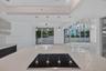 Kitchen island featuring a solid surface countertop, built-in induction cooktop, four pendant light fixtures, and multi-panel floor-to-ceiling glass s