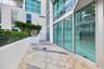 Private terrace featuring large-format stone pavers, integrated concrete planter beds with mature shrubbery, and floor-to-ceiling glass wall panels wi