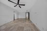 Large-format stone tile flooring with matching stone wall trim, featuring a modern matte black five-blade ceiling fan with integrated lighting