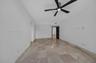 Spacious room featuring polished large-format stone tile flooring, neutral wall finishes, and a contemporary matte black ceiling fan with integrated l