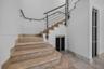 Staircase featuring stone treads, metal industrial-style railing, and built-in storage access