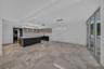 Open-concept area featuring oversized neutral-toned tile flooring, sleek flat-panel cabinetry, a central kitchen island with a stone-finish countertop