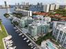 Waterfront high-rise condominium complex featuring a deep-water marina, multiple swimming pools, tiered architectural balconies, and proximity to the 