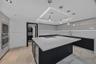 Kitchen featuring high-gloss cabinetry, a central island with a solid-surface countertop, recessed tray ceiling lighting, stainless steel built-in app