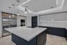 Contemporary kitchen featuring a spacious center island with a stone countertop, high-gloss cabinetry, stainless steel professional-grade appliances, 
