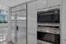 Gloss-finish cabinetry with stainless steel hardware, integrated side-by-side refrigerator, built-in microwave, and wall oven