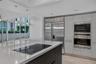 Kitchen featuring high-gloss cabinetry, a large central island with an integrated cooktop, stainless steel professional-grade appliances, recessed lig
