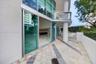 Expansive stone-paved terrace with contrasting linear accents, floor-to-ceiling glass sliding doors, elevated glass-paneled balcony, and structural co