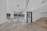 Double-height ceilings, floor-to-ceiling glass wall, polished stone flooring, custom multi-light chandelier, and stone staircase