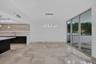 Open-concept interior featuring large-format tile flooring, high-gloss cabinetry, a quartz waterfall island, modern linear architectural lighting, and