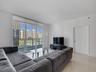 Floor-to-ceiling windows with roller shades, balcony access, and large-format tile flooring