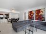Open floor plan featuring polished tile flooring, recessed lighting, and kitchen with dark-finish cabinetry and stone-surface breakfast bar