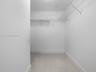 Storage space featuring white walls, large-format tile flooring, and integrated white wire shelving
